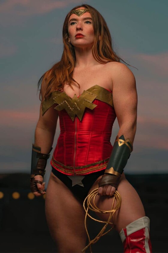 Red haired woman dress in wonder woman costume standing in a neutral pose muscular arms on display. The Superman Problem.