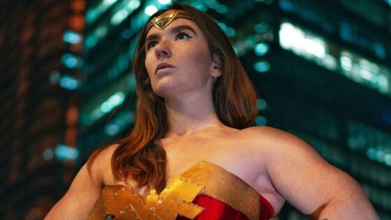 Red haired woman dressed in a Wonder Woman costume striking a heroic pose.