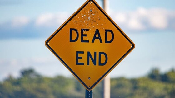A photo of a U.S. style dead end sign in front of a sky with scattered clouds.