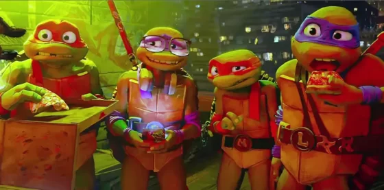 Raphael is on the left holding a pizza in a pizza box. Donatello is next to him with a bashful expression on his face. Michelangelo looks embarrassed while Leonardo is in the middle of eating a pizza slice.