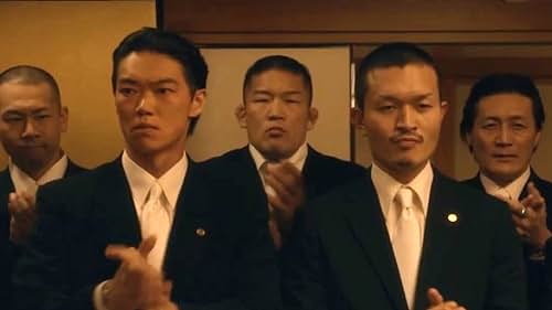 Sato is clapping with members of the Chihara-kai Yakuza.