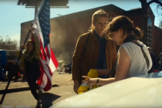 A female flag bearer runs past Lee and Jessie while strapped with a explosive device.